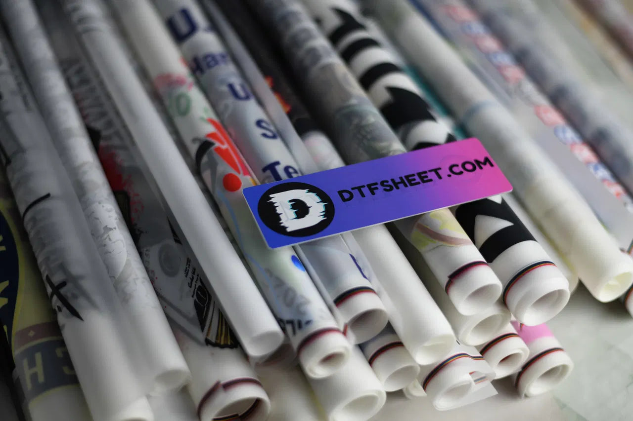 Rolled DTF transfer prints stacked together, representing a high-volume custom printing operation.